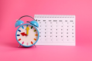 Photo of Alarm clock and calendar on pink background. Reminder concept