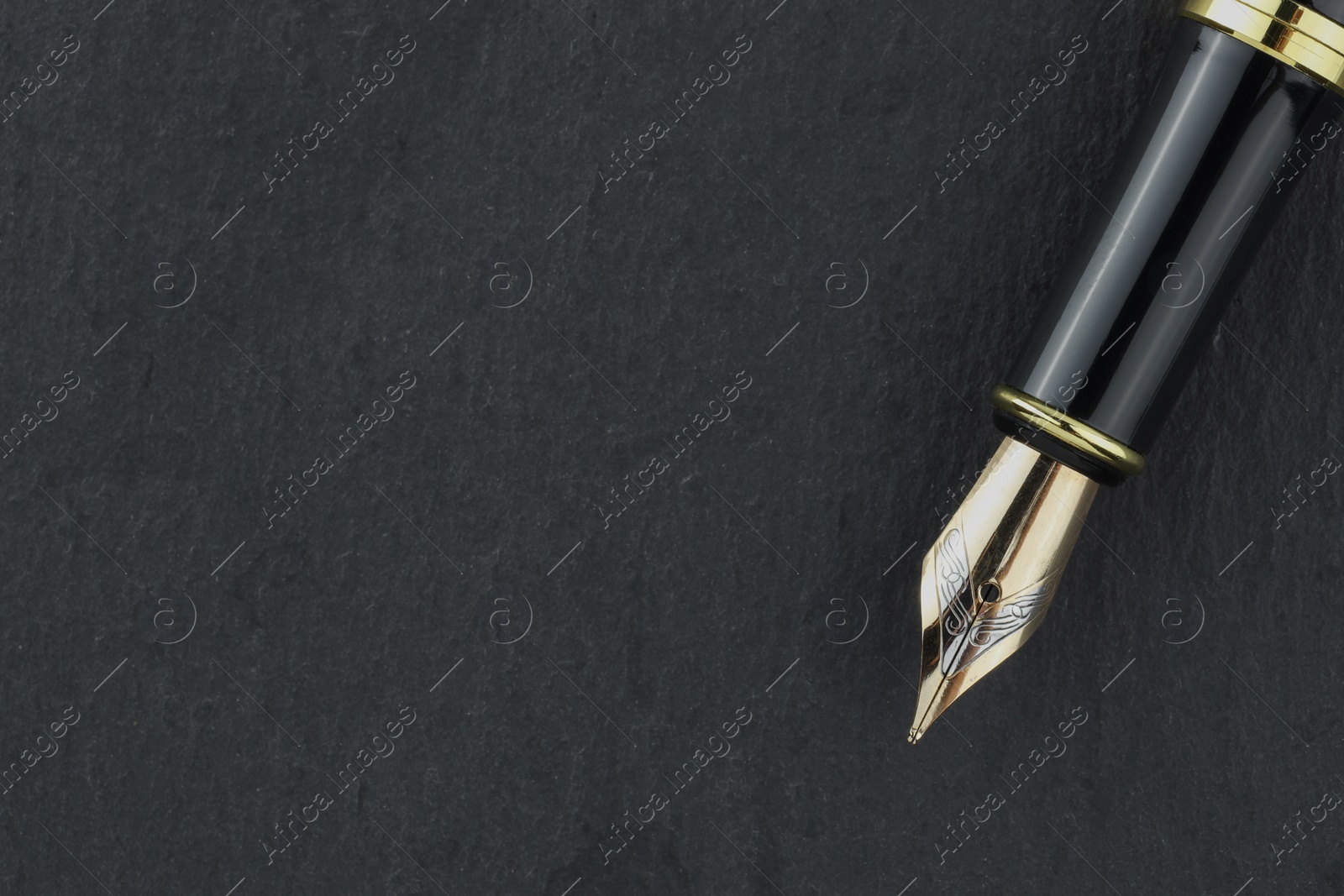 Photo of Stylish fountain pen on dark textured table, top view. Space for text