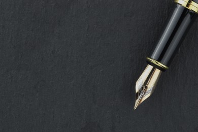 Stylish fountain pen on dark textured table, top view. Space for text