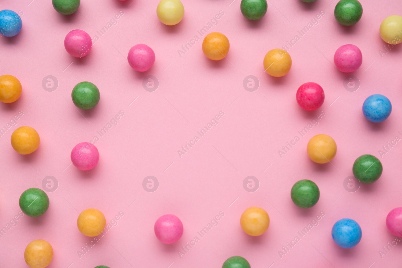 Photo of Many bright chewy gumballs on pink background, flat lay. Space for text