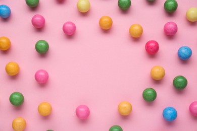 Photo of Many bright chewy gumballs on pink background, flat lay. Space for text