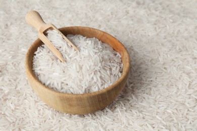 Photo of Raw basmati rice, bowl and scoop as background, closeup