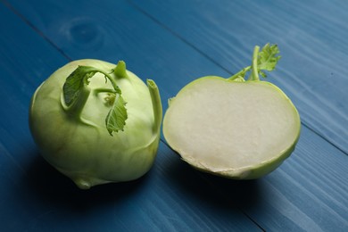 Photo of Whole and cut kohlrabi plants on blue wooden table