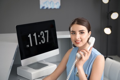 Photo of Beauty salon receptionist talking on phone at desk