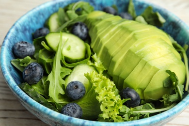 Delicious avocado salad with blueberries in bowl on table, closeup