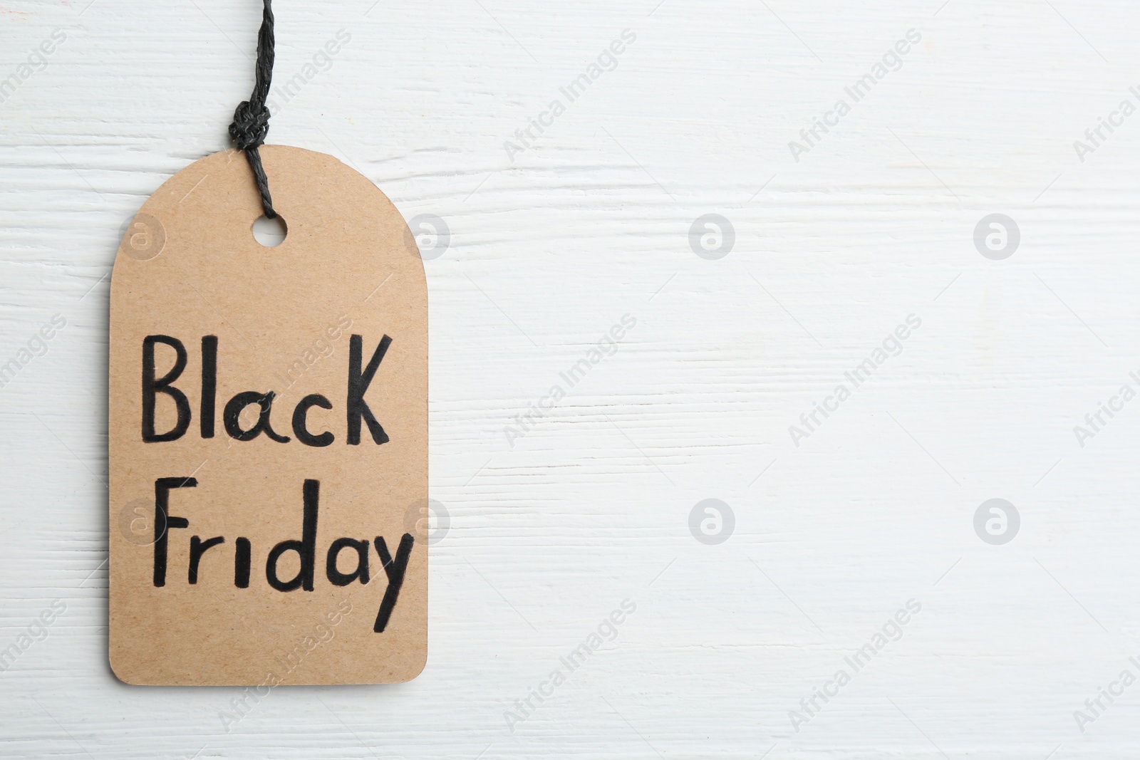 Photo of Top view of tag with words BLACK FRIDAY on white wooden background. Space for text