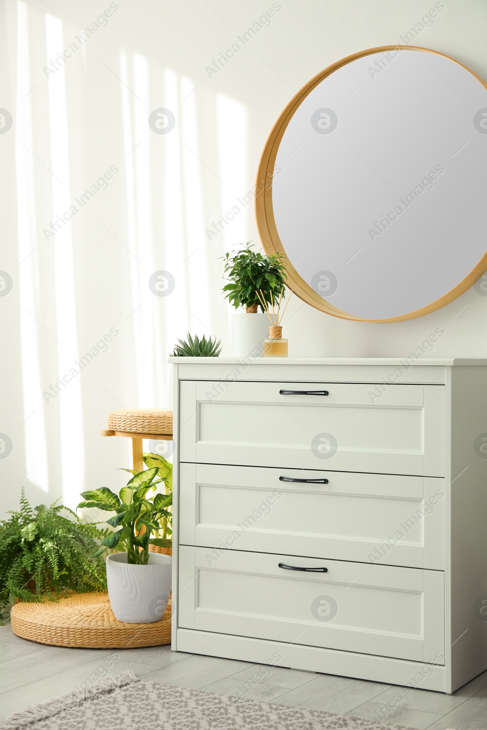 Photo of Stylish room interior with chest of drawers and round mirror