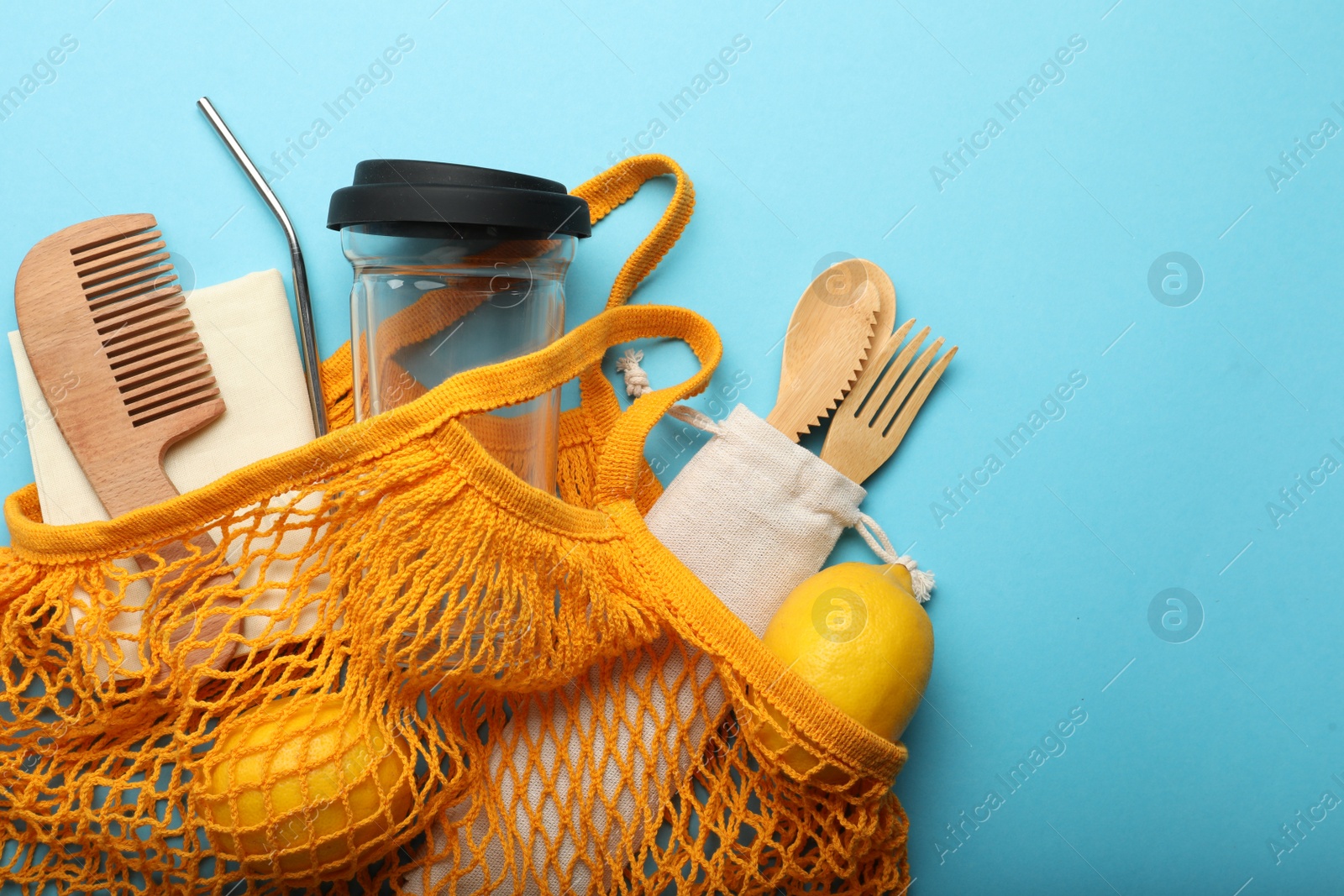 Photo of Bag with eco friendly products on turquoise background, top view