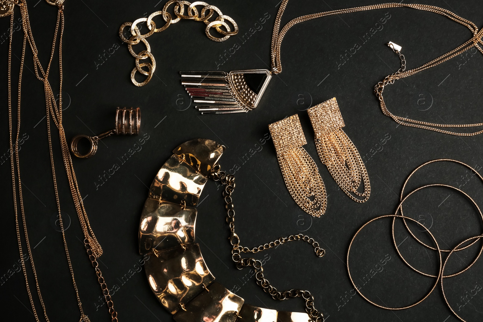 Photo of Set of gold jewelry on black background, flat lay