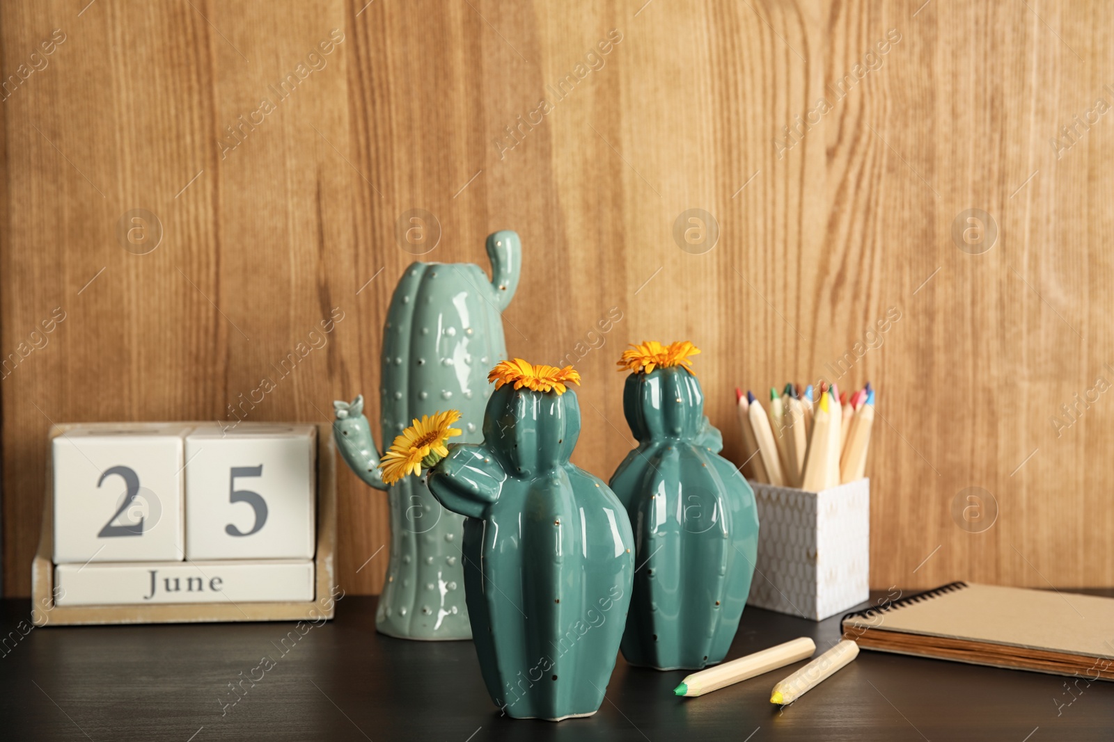 Photo of Trendy cactus shaped vases and stationery on table against wooden background. Creative decor
