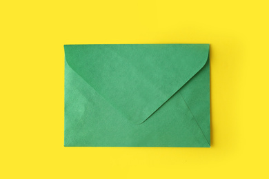 Green paper envelope on yellow background, top view