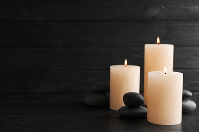 Burning candles and spa stones on table. Space for text