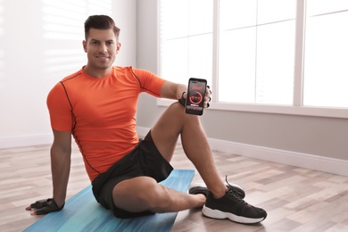 Man showing smartphone with fitness app indoors