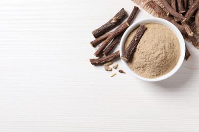 Photo of Powder in bowl and dried sticks of liquorice root on white table, flat lay. Space for text