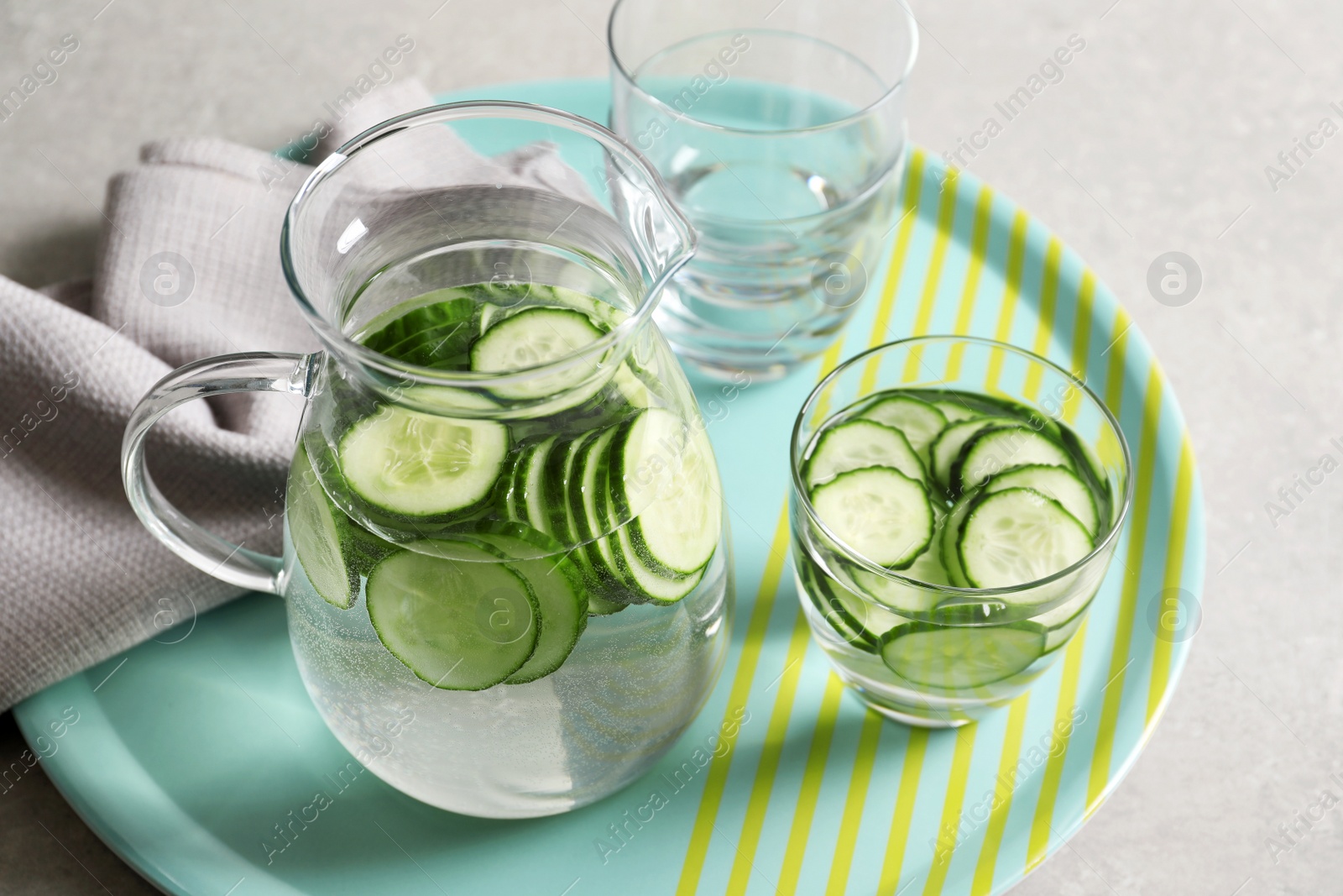 Photo of Glasses and jug of fresh cucumber water on tray