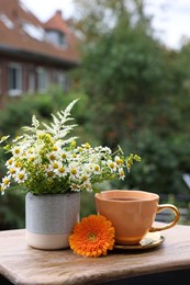 Cup of delicious chamomile tea and fresh flowers outdoors