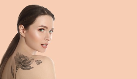 Young woman with beautiful tattoo of flower and butterfly on pale peach background, space for text. Banner design