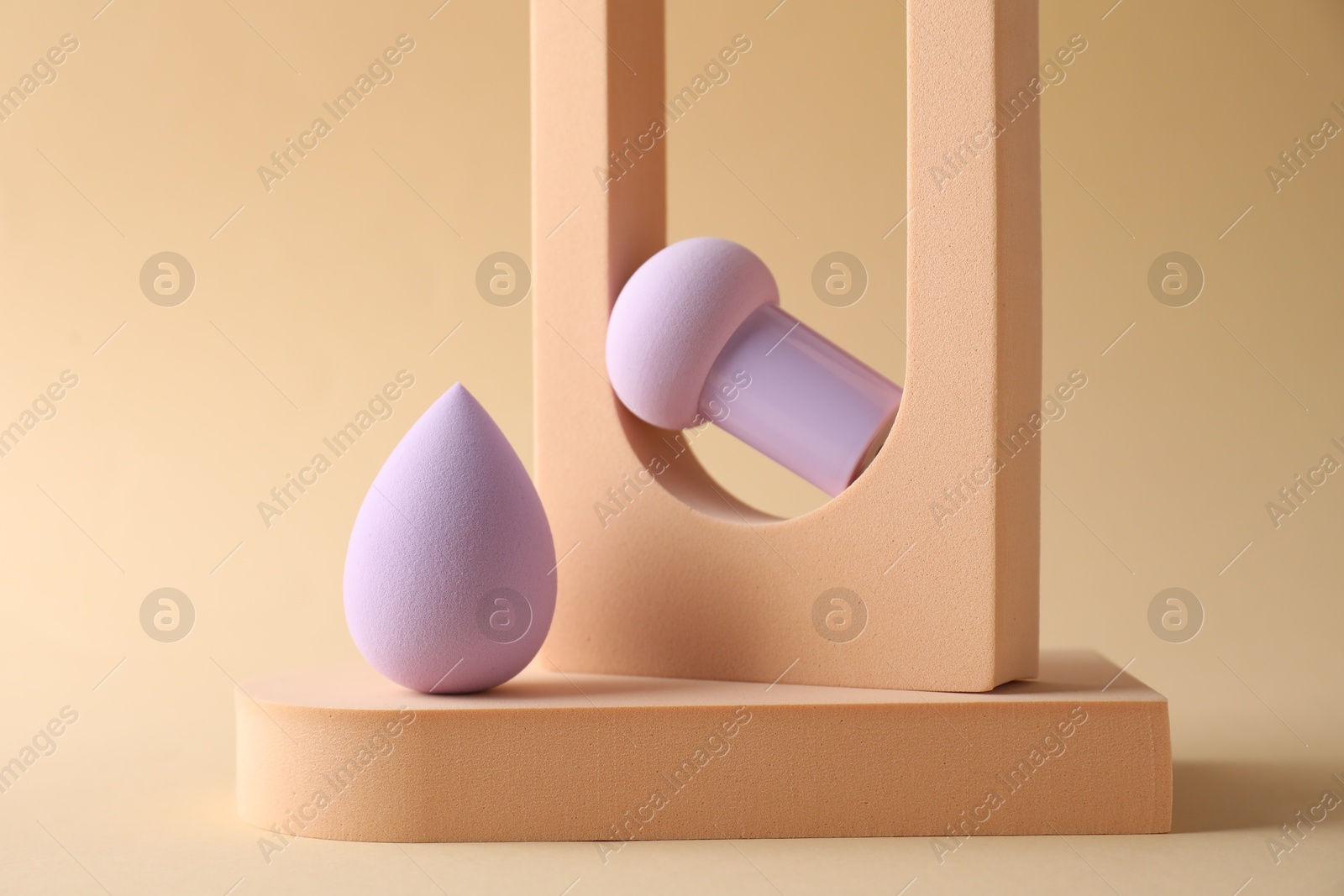 Photo of Stylish presentation of makeup sponges on beige background