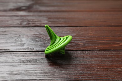 Photo of One green spinning top on wooden table, closeup