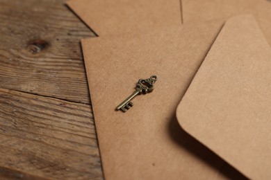 Paper envelopes and small key on wooden table, closeup