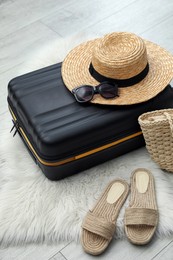 Suitcase packed for trip and summer accessories on floor indoors