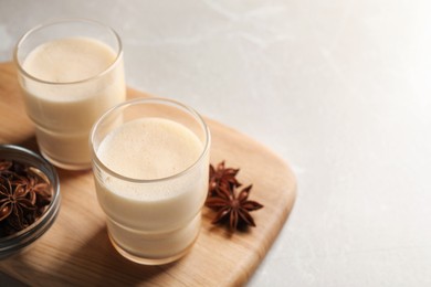 Photo of Glasses of delicious eggnog with anise on grey marble table. Space for text