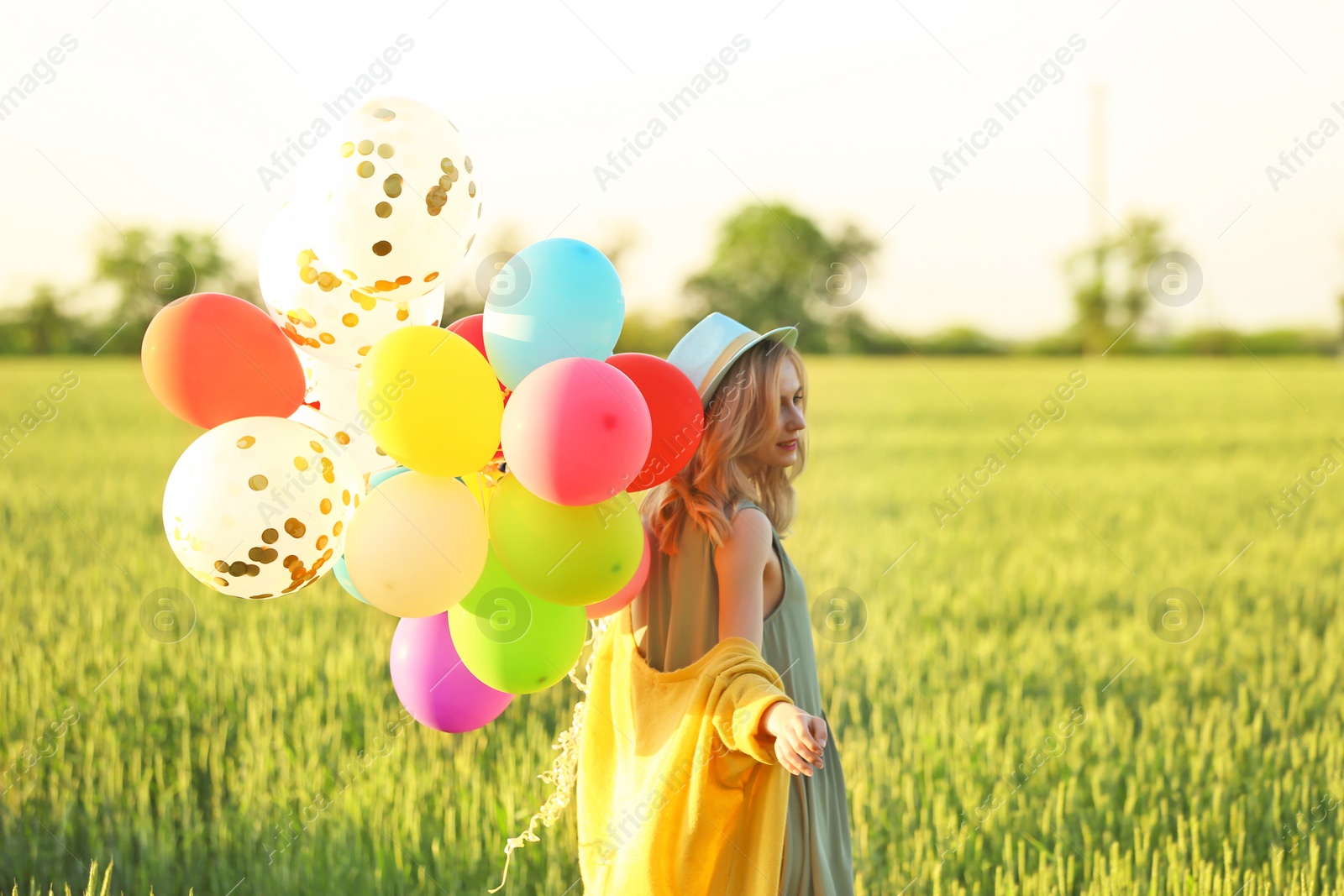 Photo of Young woman with colorful balloons in field on sunny day