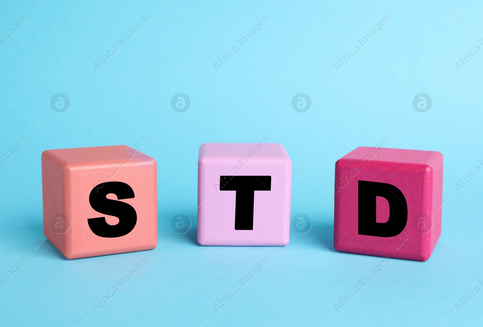 Photo of Abbreviation STD made with cubes on light blue background