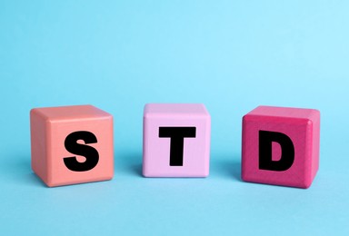 Abbreviation STD made with cubes on light blue background