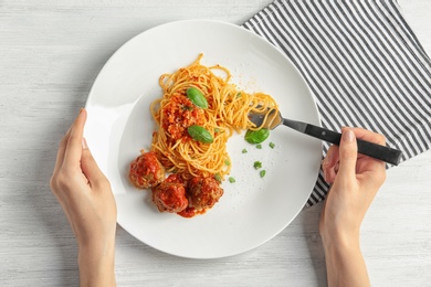 Photo of Woman having pasta with meatballs and tomato sauce at table, closeup