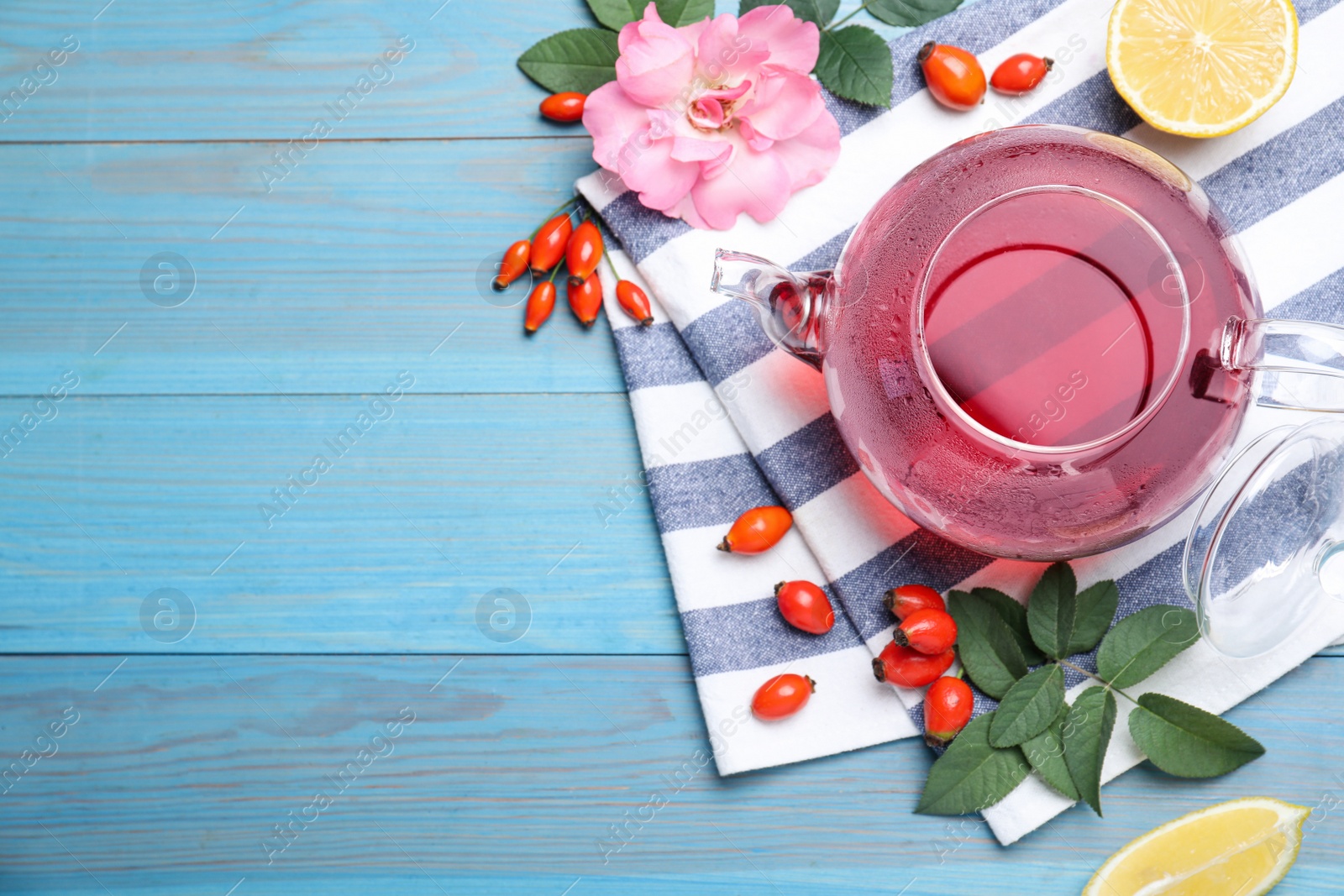 Photo of Fresh rose hip tea and berries on blue wooden table, flat lay. Space for text