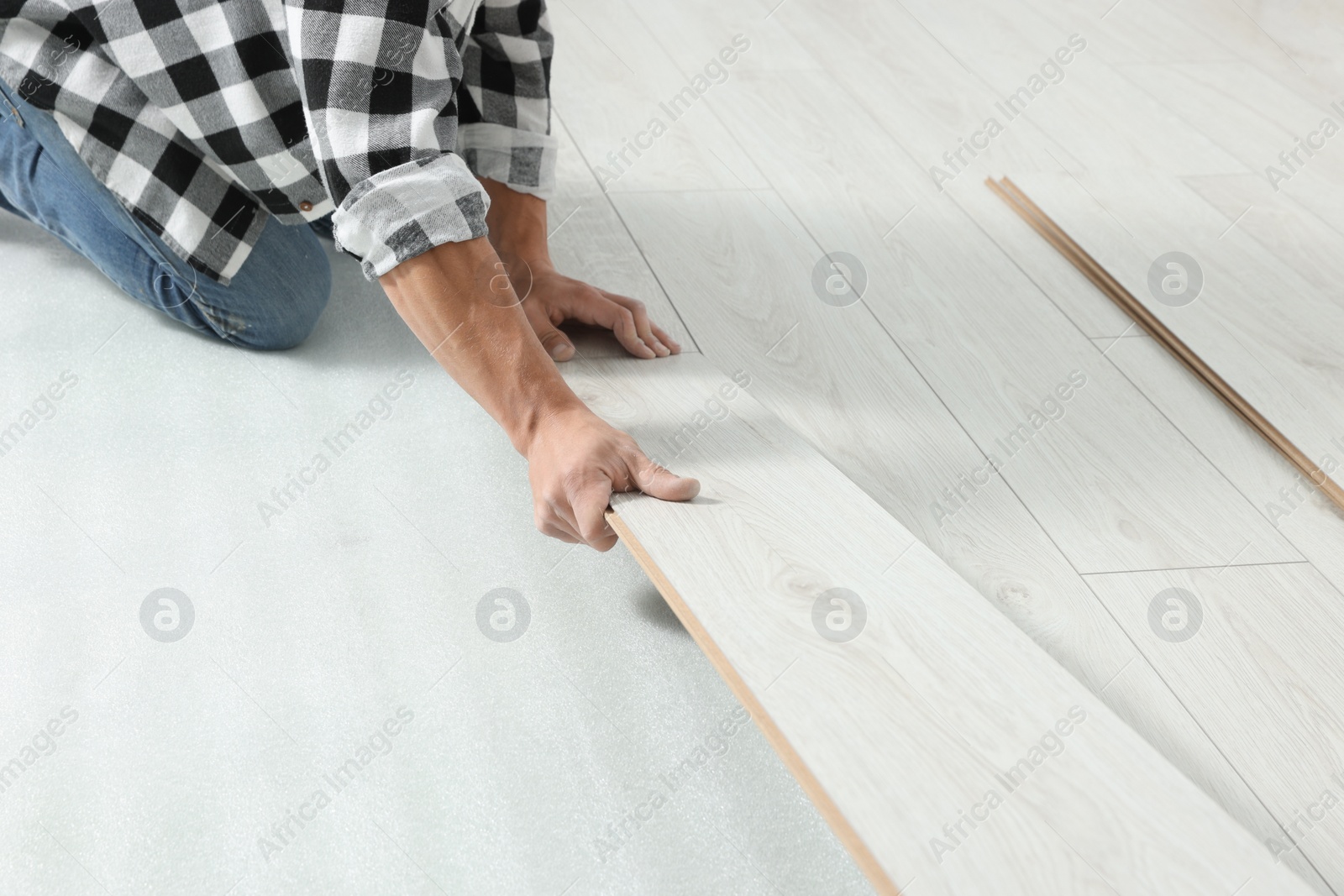 Photo of Professional worker installing new laminate flooring, closeup