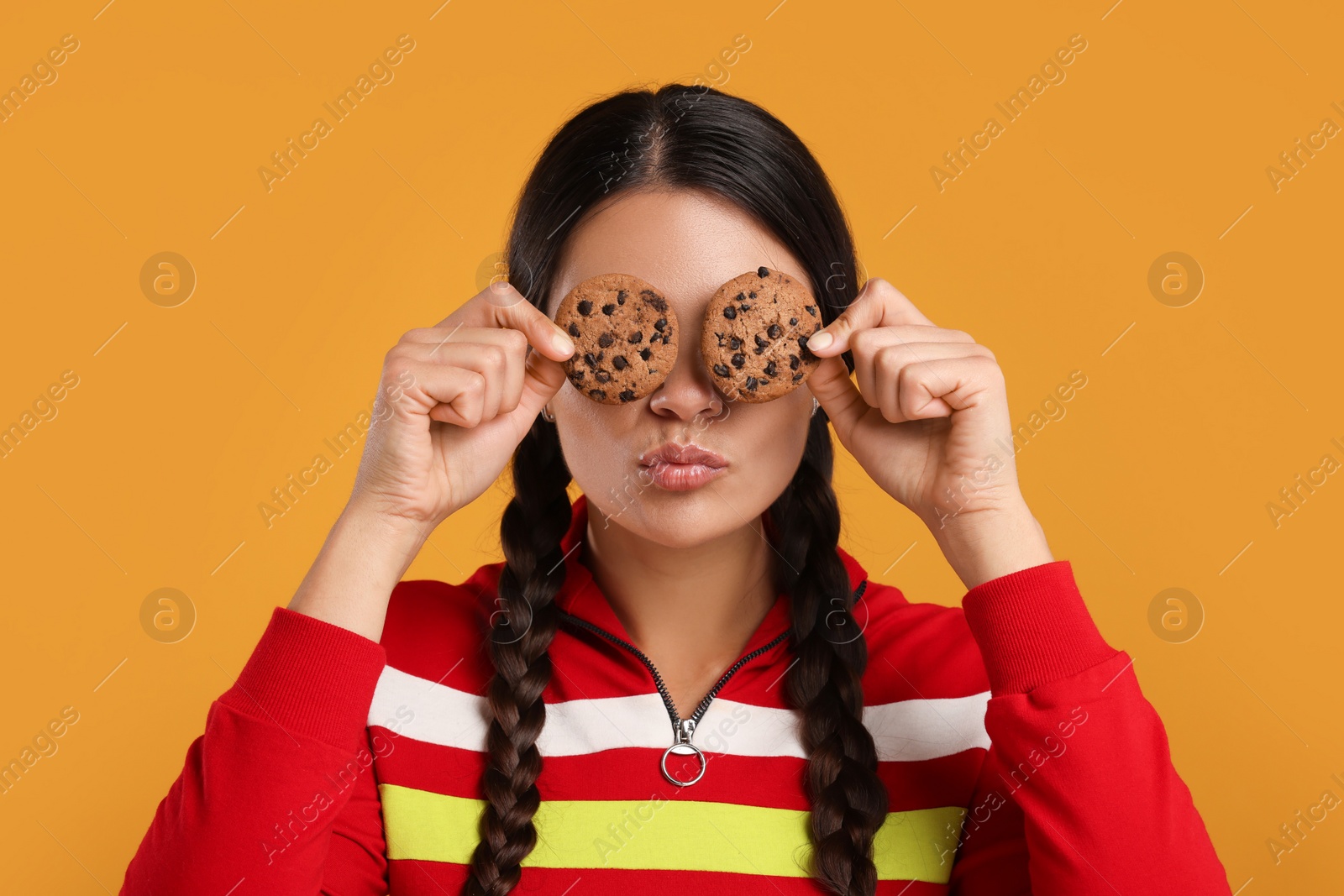 Photo of Young woman with chocolate chip cookies on orange background