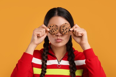 Photo of Young woman with chocolate chip cookies on orange background