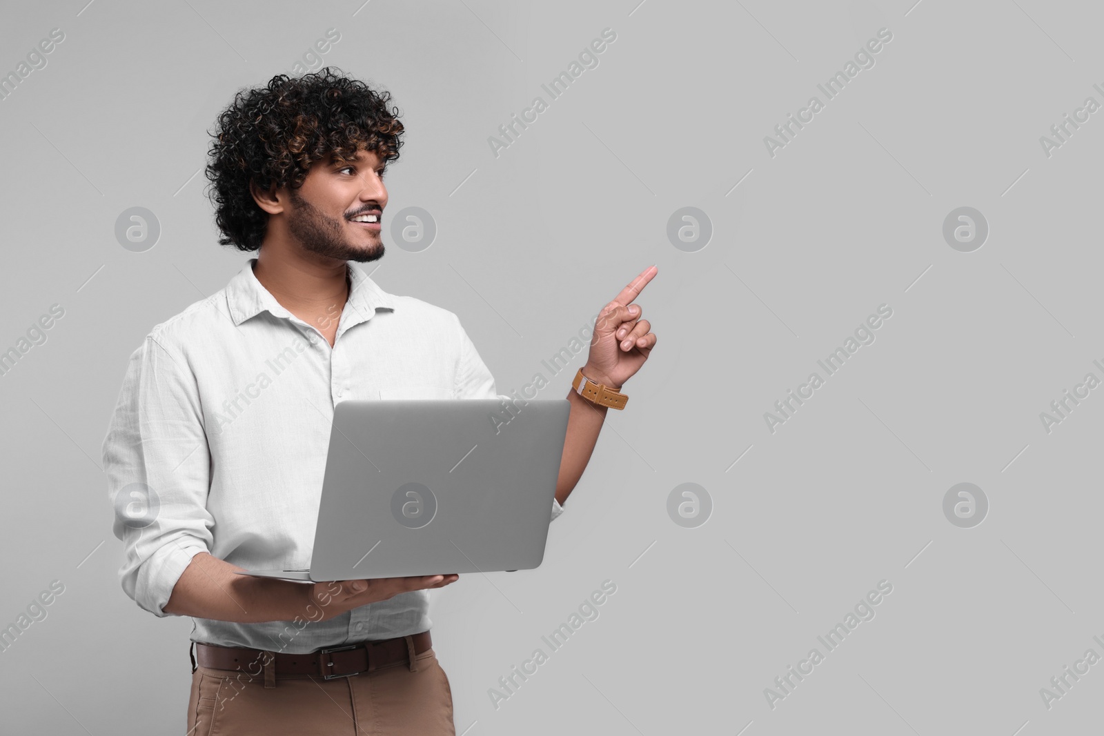 Photo of Smiling man with laptop on light grey background, space for text