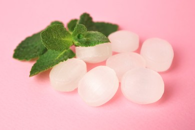 Cough drops and mint leaves on pink background