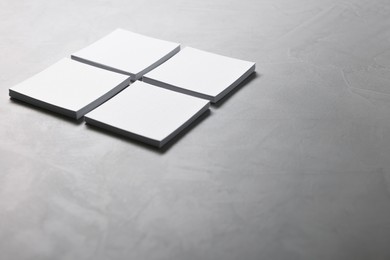 Blank paper sheets on grey textured table, closeup. Mockup for design