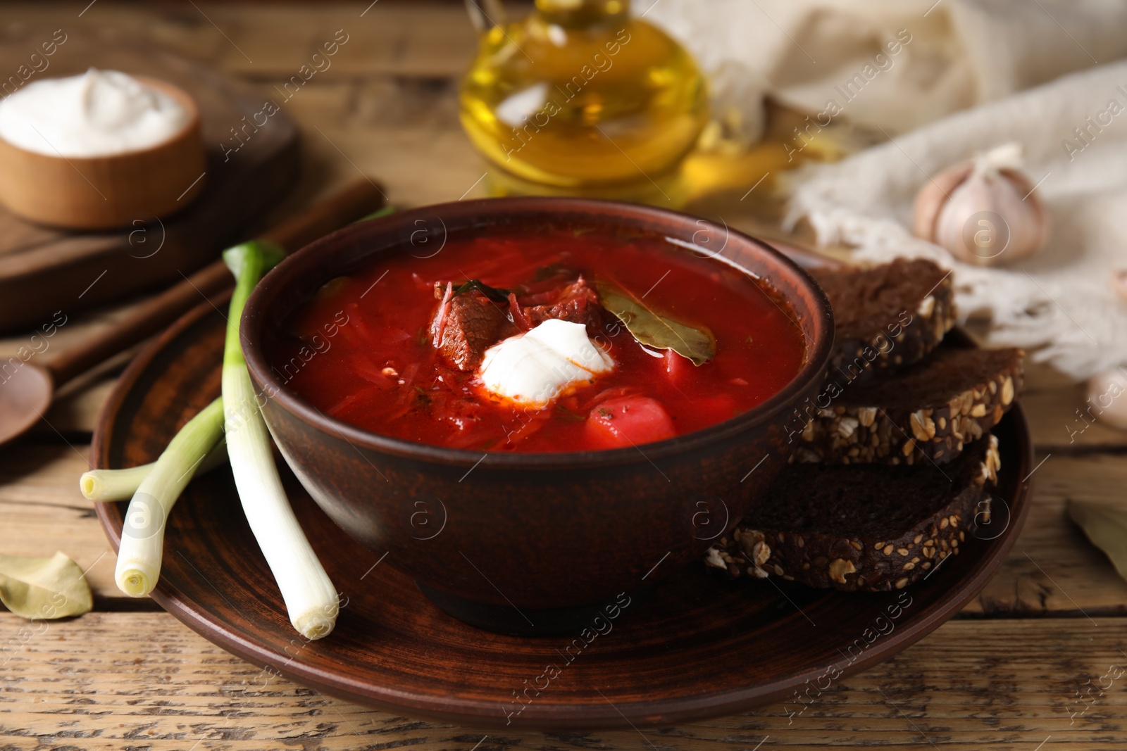 Photo of Clay bowl with Ukrainian borsch served on wooden table