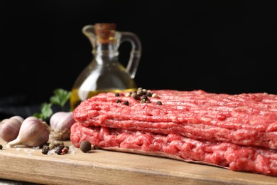 Photo of Raw ground meat, peppercorns and garlic on table, closeup