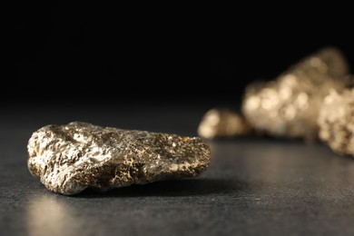 Photo of Shiny gold nugget on grey surface, closeup. Space for text