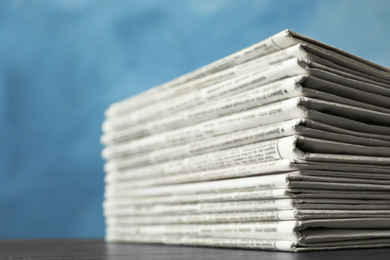 Stack of newspapers on blue background, closeup. Journalist's work