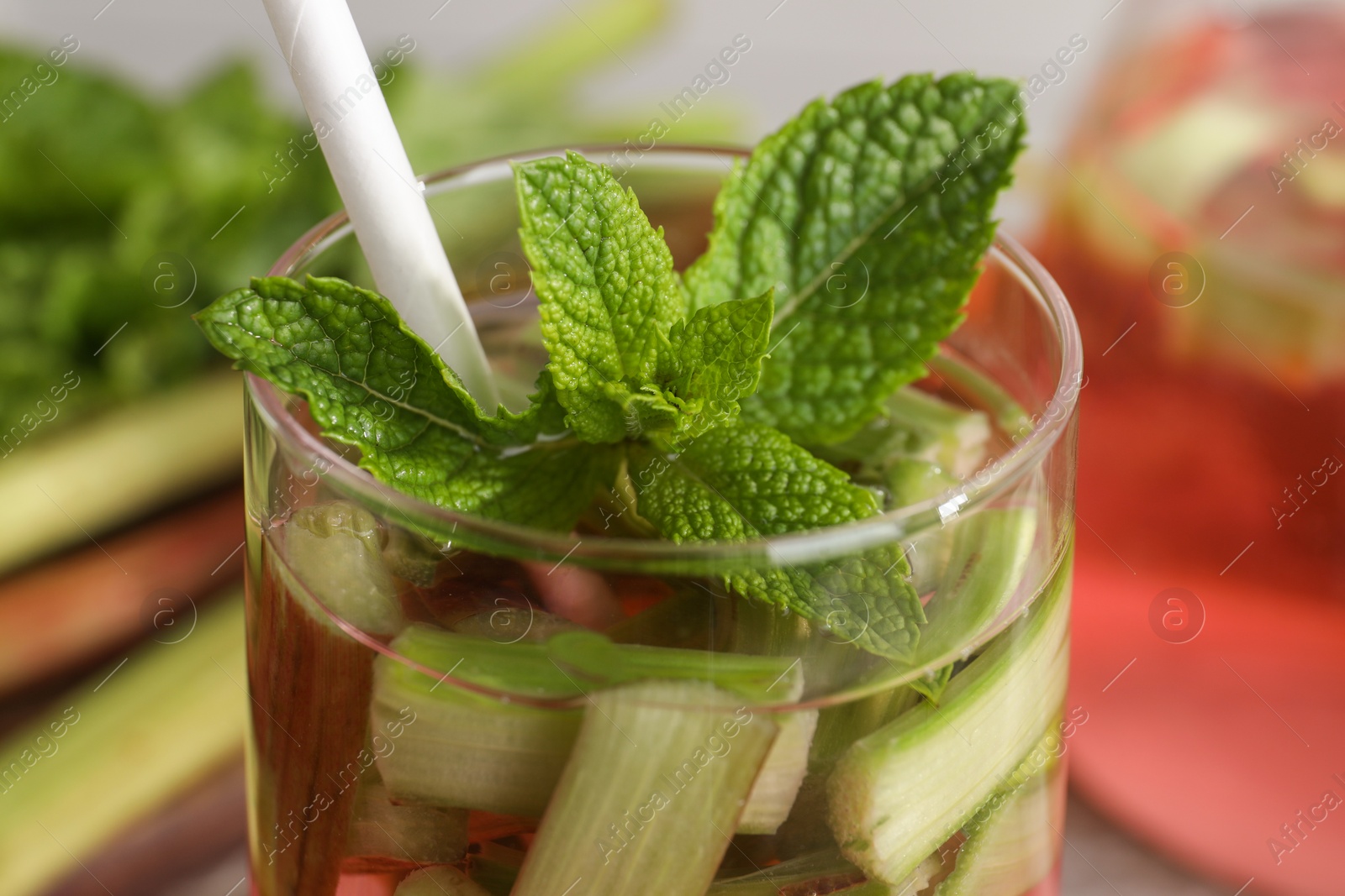 Photo of Glass of tasty rhubarb cocktail on blurred background, closeup