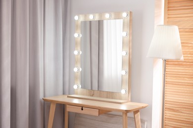 Photo of Beautiful mirror with light bulbs and lamp in makeup room