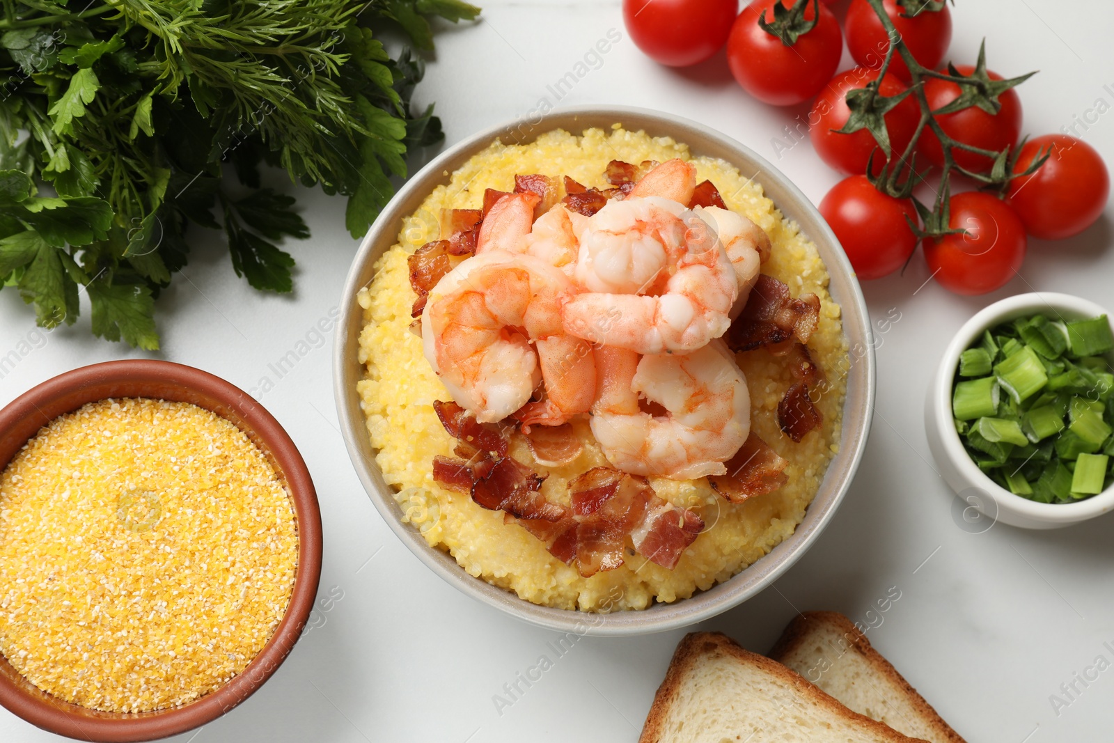 Photo of Fresh tasty shrimps, bacon and grits in bowl on white table, flat lay