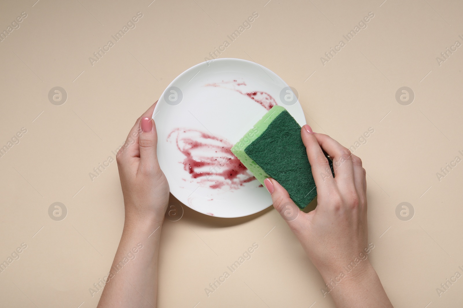 Photo of Woman washing dirty plate with sponge on beige background, top view