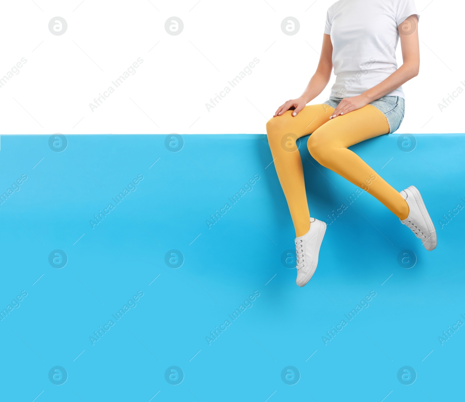 Photo of Woman wearing yellow tights and stylish shoes sitting on color background, closeup. Space for text