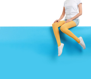 Woman wearing yellow tights and stylish shoes sitting on color background, closeup. Space for text