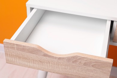 Stylish desk with open empty drawer in office, closeup