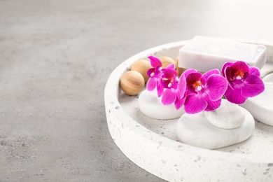 Tray with spa stones, orchid flowers and soap on grey table