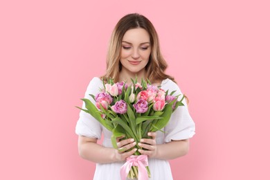 Photo of Happy young woman with bouquet of beautiful tulips on pink background